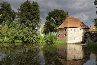 Building by lake against sky