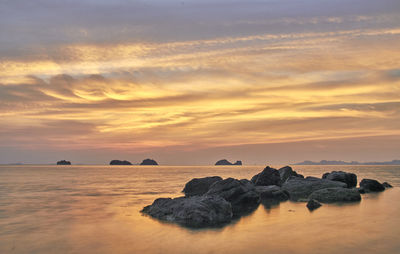 Rocks on sea against sky during sunset