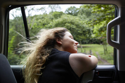 Side view of young woman sitting in car