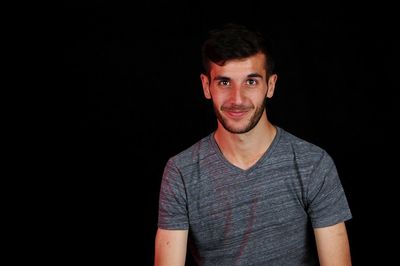 Portrait of young man against black background