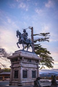 Statue in city against cloudy sky