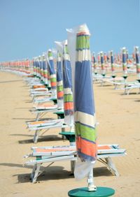 Row of chairs on beach against clear sky