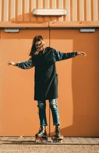 Full length of young woman standing against wall