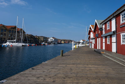 Sailboats moored on harbor by buildings against sky in city