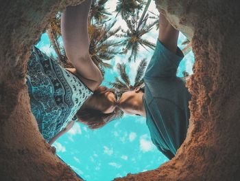 Low section of woman standing on tree trunk against sky