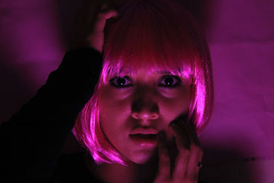 Close-up portrait of young woman in illuminated room