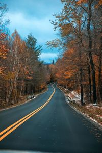 Road amidst trees against sky during autumn