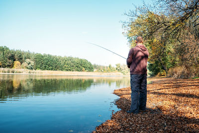 Fisherman with spinning rod on the autumn lake. fisherman with spinning in his hands catching fish