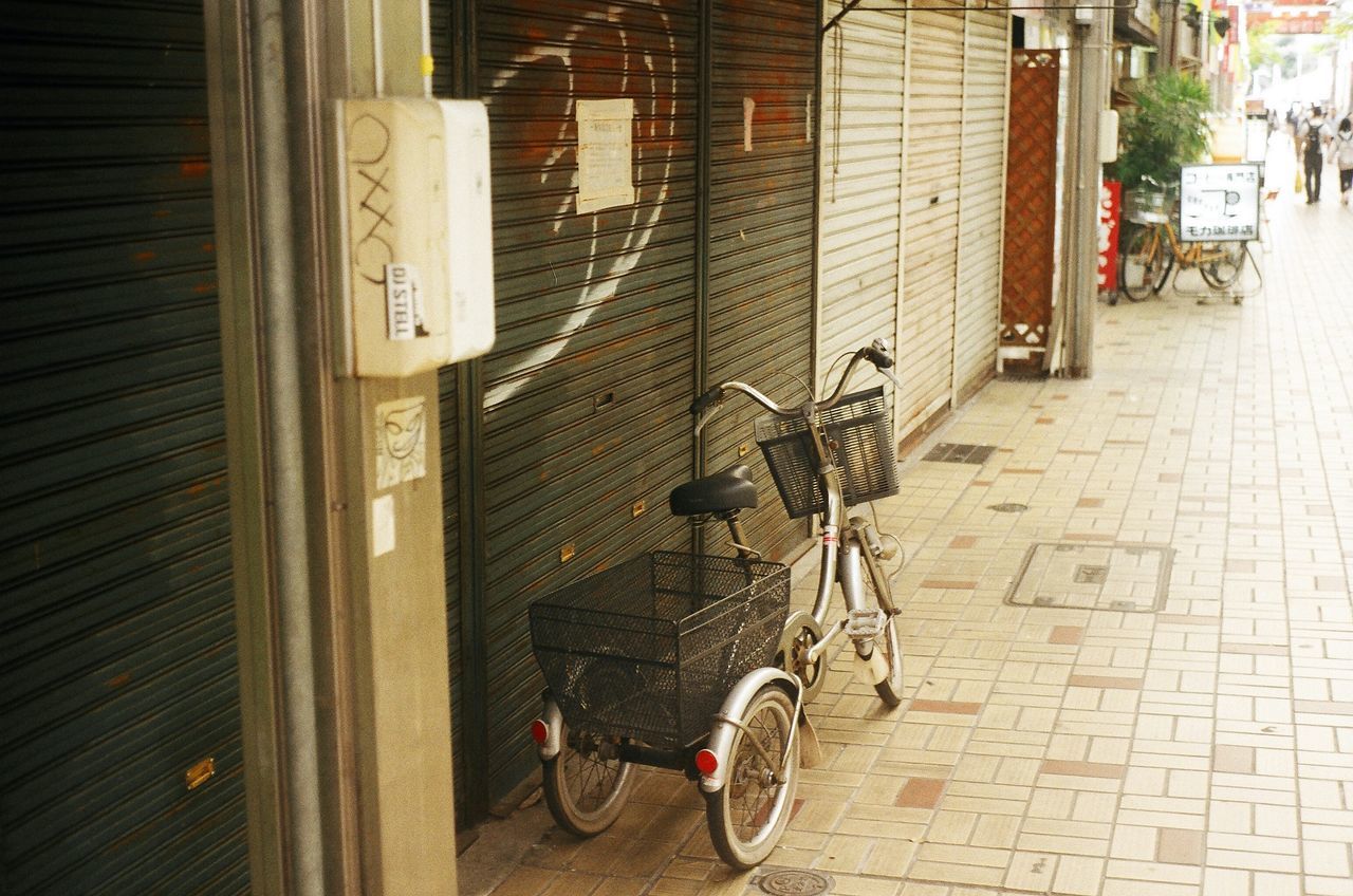 bicycle, transportation, land vehicle, mode of transport, building exterior, architecture, street, built structure, stationary, parked, parking, sidewalk, city, wall - building feature, road, day, outdoors, cobblestone, car, building