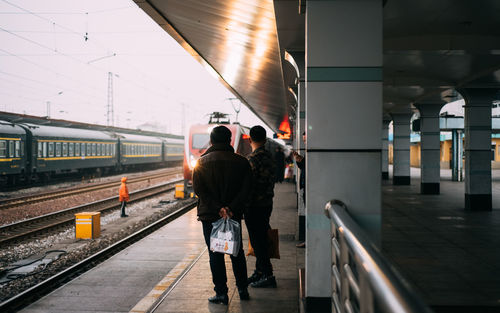 Rear view of people walking on railroad station platform