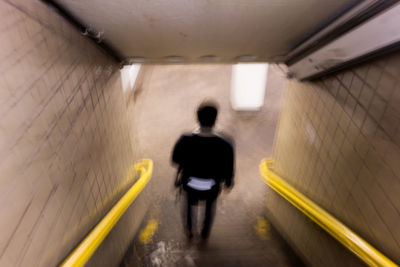 Rear view of man walking in subway tunnel