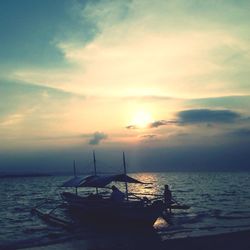 Boats in sea at sunset