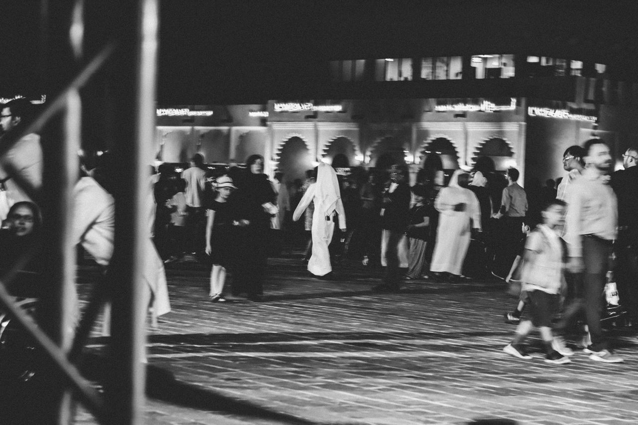 GROUP OF PEOPLE WALKING ON ZEBRA CROSSING IN CITY AT NIGHT