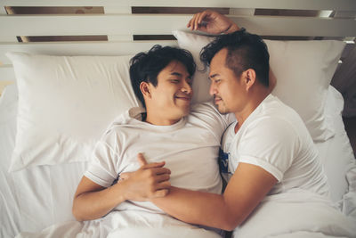 Loving gay couple lying on bed at home