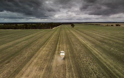 Scenic view of agricultural field against sky getting fertiliser spread in overcast weather. 