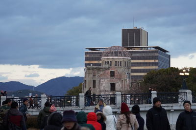 People at modern buildings in city against sky