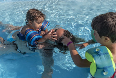 Single-parent family playing in the swimming pool. summer arrives in the northern hemisphere.