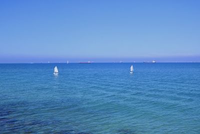 Sailboat in sea against clear blue sky