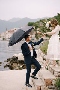 Side view of couple standing against sky