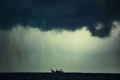 Silhouette people sailing on sea against sky