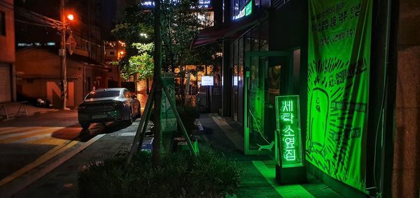 Cars on street amidst illuminated buildings in city at night