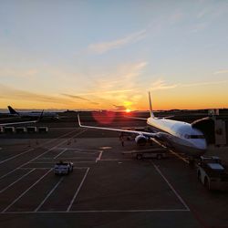 Vehicles on road against sky during sunset