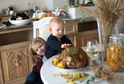 Cute siblings by food and drink at table