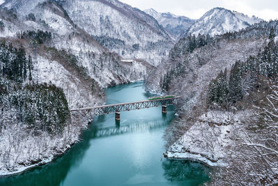 Scenic view of river amidst mountains during winter