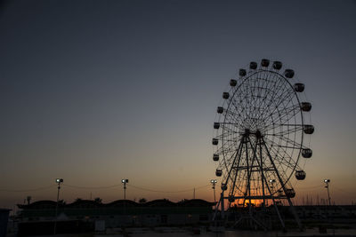 Low angle view of ferris wheel against sky at sunset