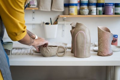 Workplace of craft ceramist with handmade ceramics. female artist shape potter kitchenware in studio
