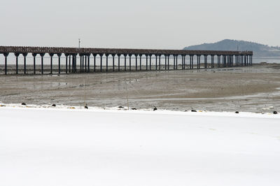 Bridge over sea against clear sky during winter