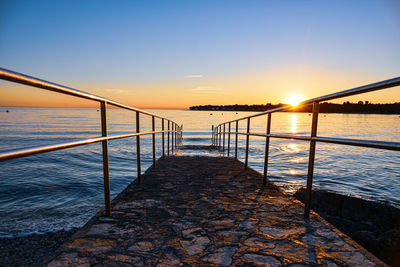 Pier over sea against sky during sunset