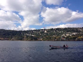 Boat sailing in river against cloudy sky