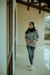 Portrait of young woman standing against wall