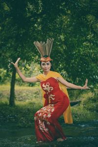 Young woman wearing traditional clothing dancing in forest