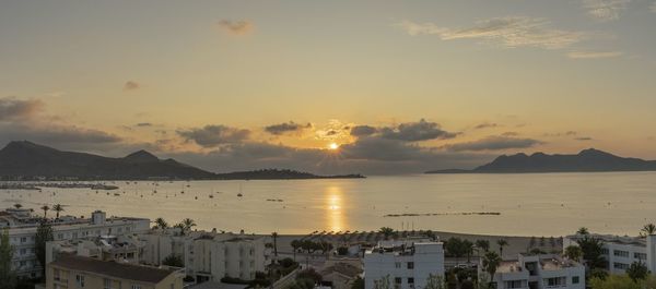 High angle view of sea and buildings against sky during sunset