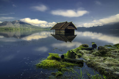 House by lake and mountains against sky