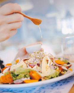 Cropped hand pouring drink on salad