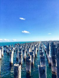 Wooden posts in sea against sky