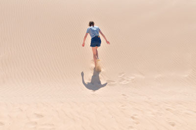 Rear view of man walking on sand
