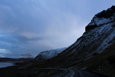 Road by mountains against sky during winter