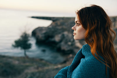 Side view of young woman looking away against sea