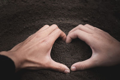 Close-up of hands making heart shape on sand
