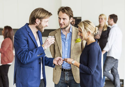Mid adult businessman giving business card to female colleague in office