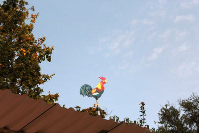 Low angle view of a bird sculpture on roof against sky
