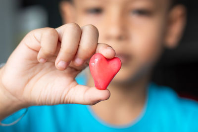 Close-up of boy holding heart shape hand