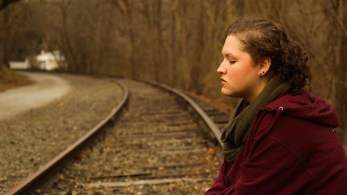 Portrait of teenage girl standing on railroad track