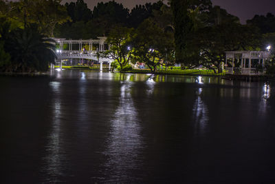 Illuminated bridge over river in city at night