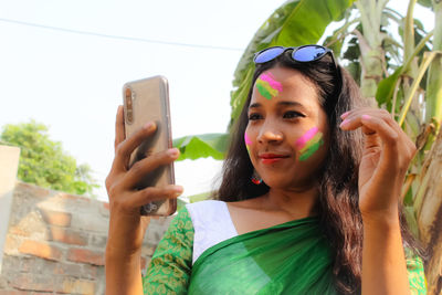 Portrait of woman photographing through mobile phone