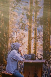 Side view of man sitting on seat in forest